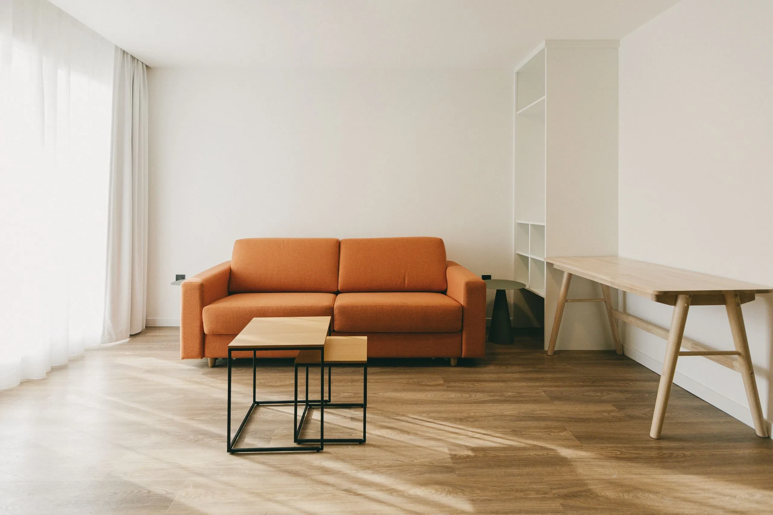 Salon moderne avec canapé orange et tables en bois.