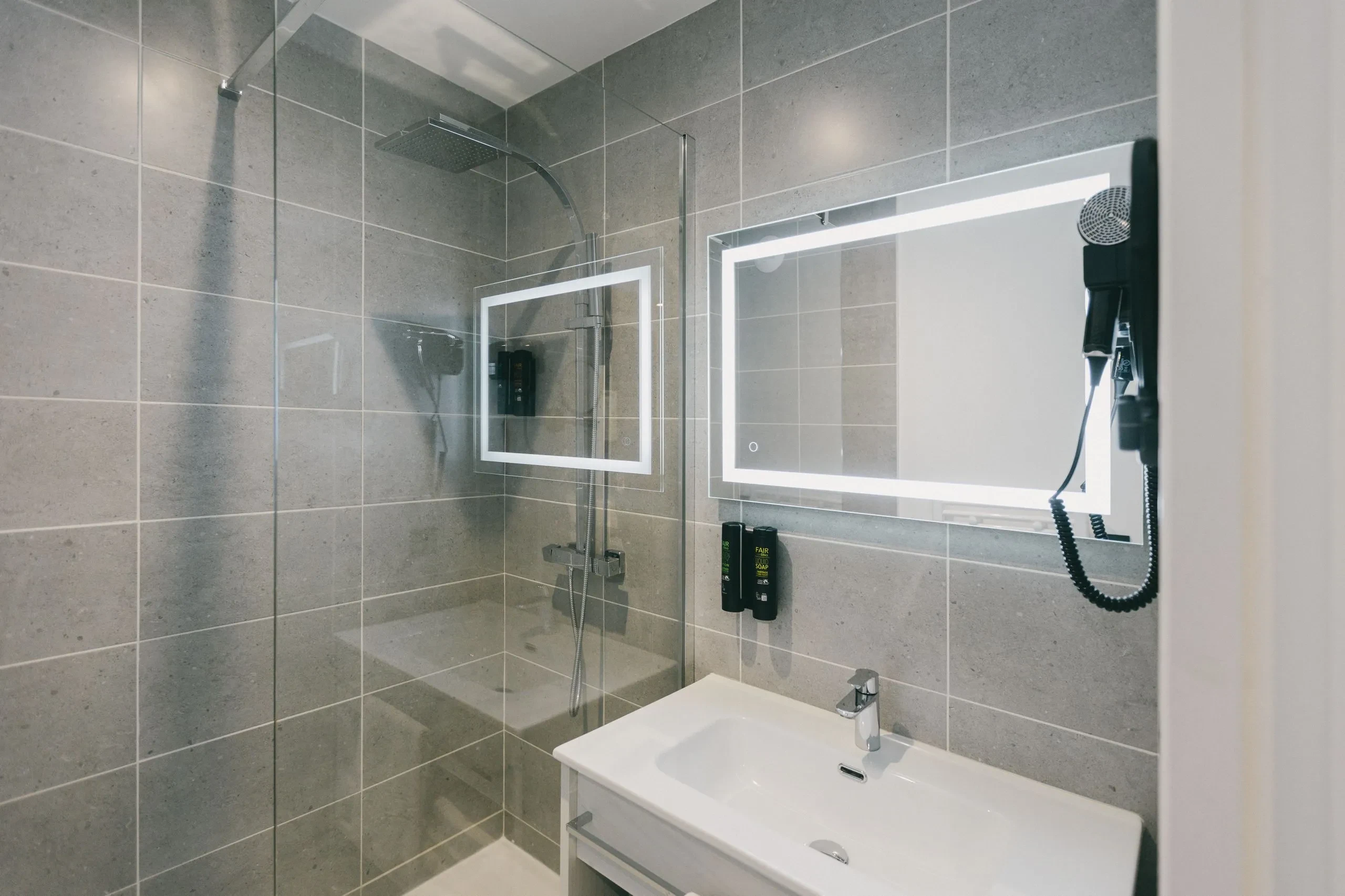 Salle de bain moderne avec douche et vasque.