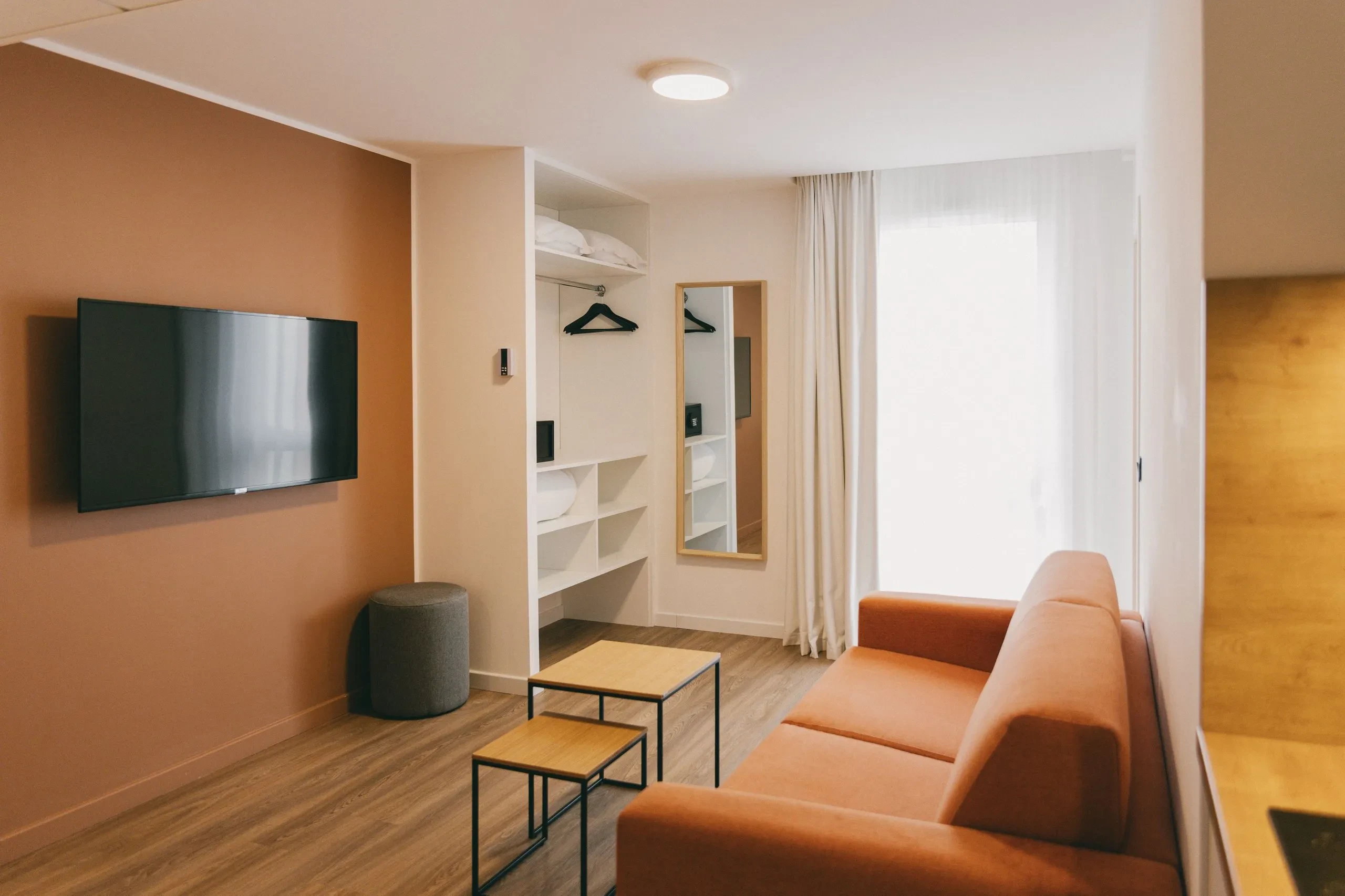 Salon moderne avec canapé orange et télé murale.