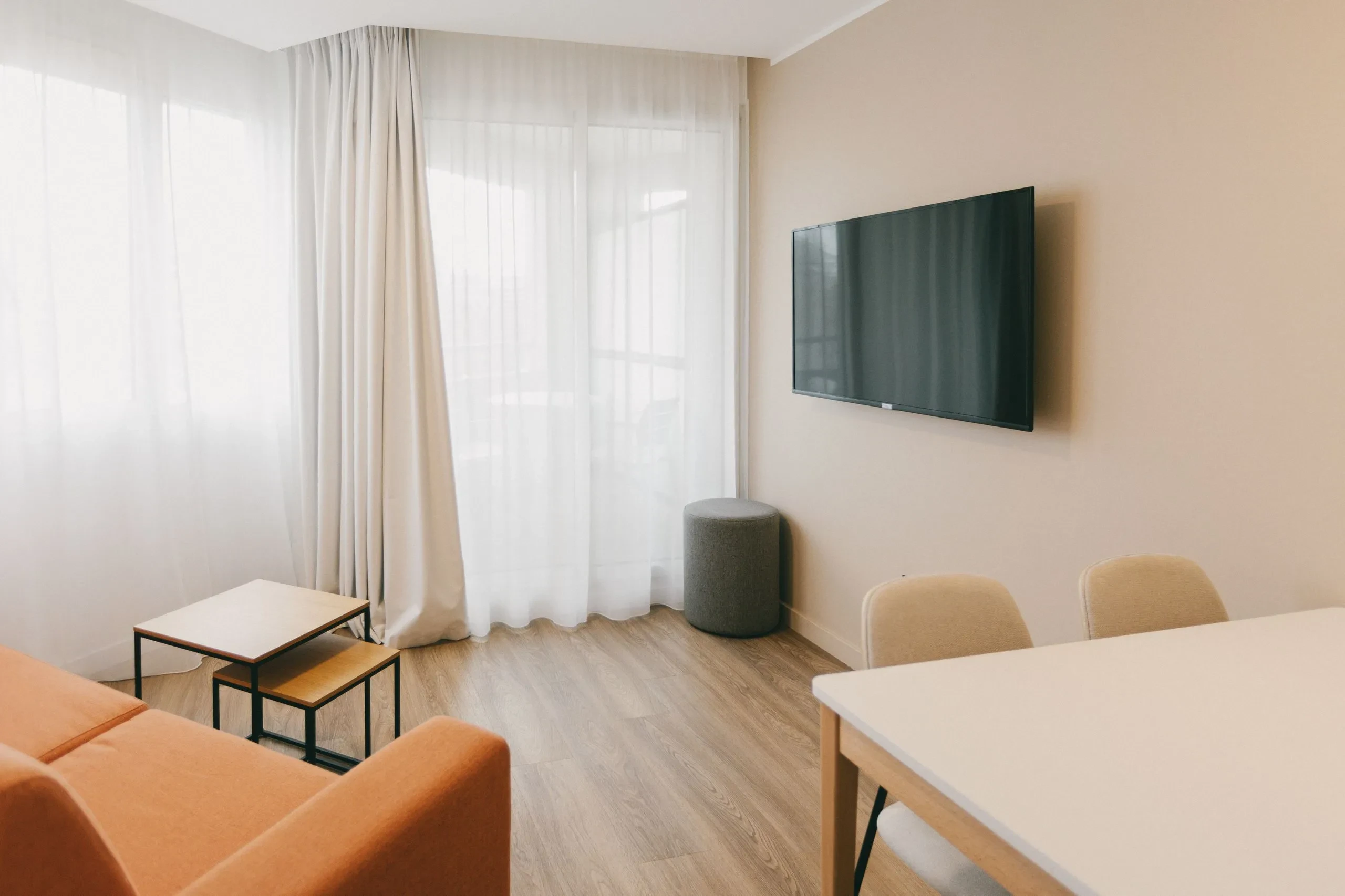 Salon moderne avec télévision murale et canapé orange.