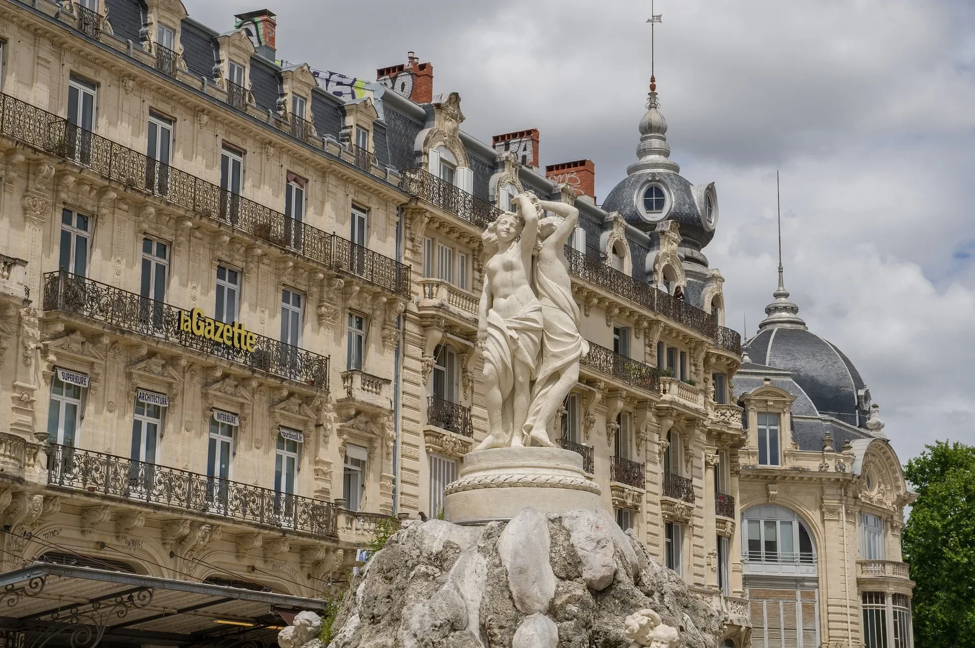 Statue front d'un bâtiment historique, ciel nuageux.