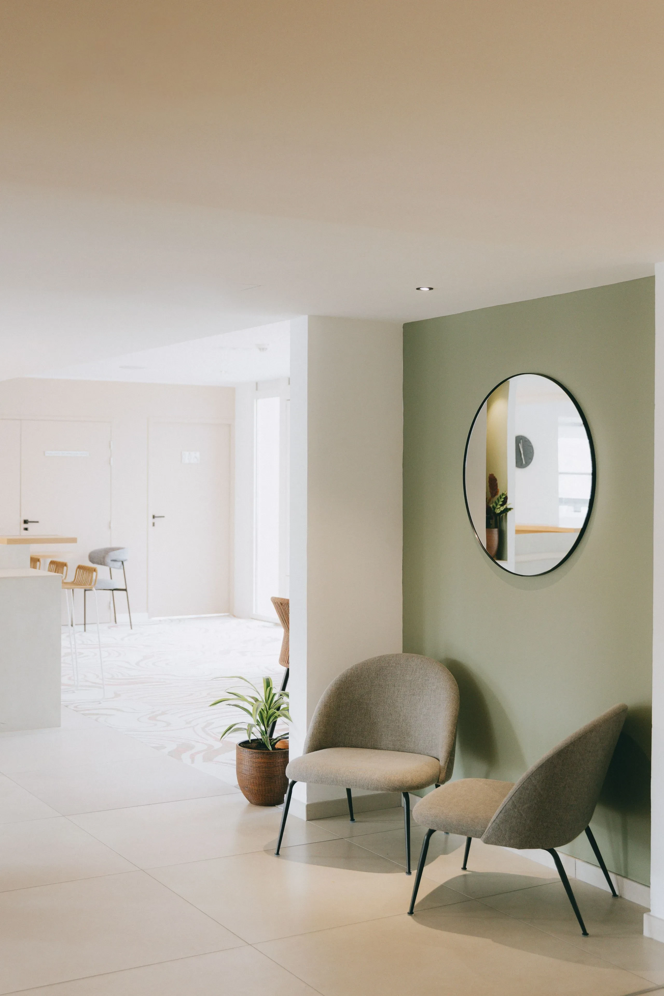 Intérieur moderne avec fauteuils, miroir et plante.