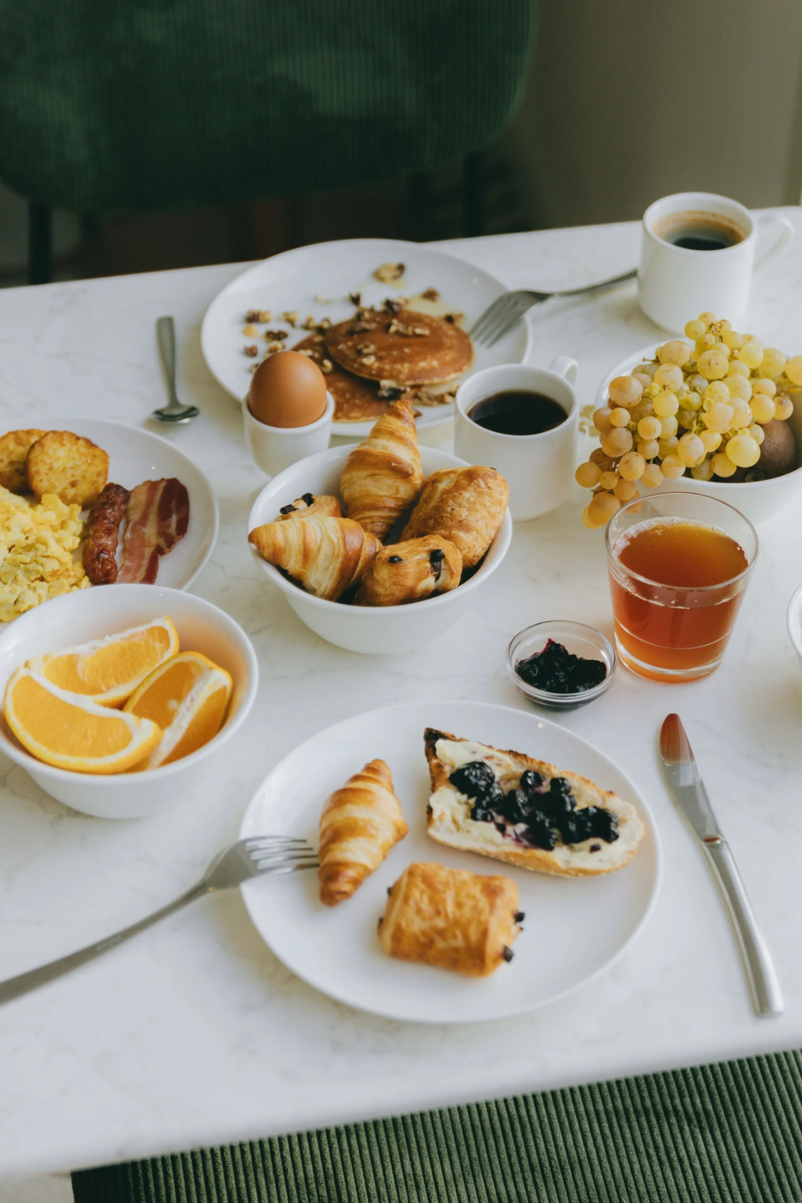 Petit-déjeuner sur une table avec croissants et fruits.
