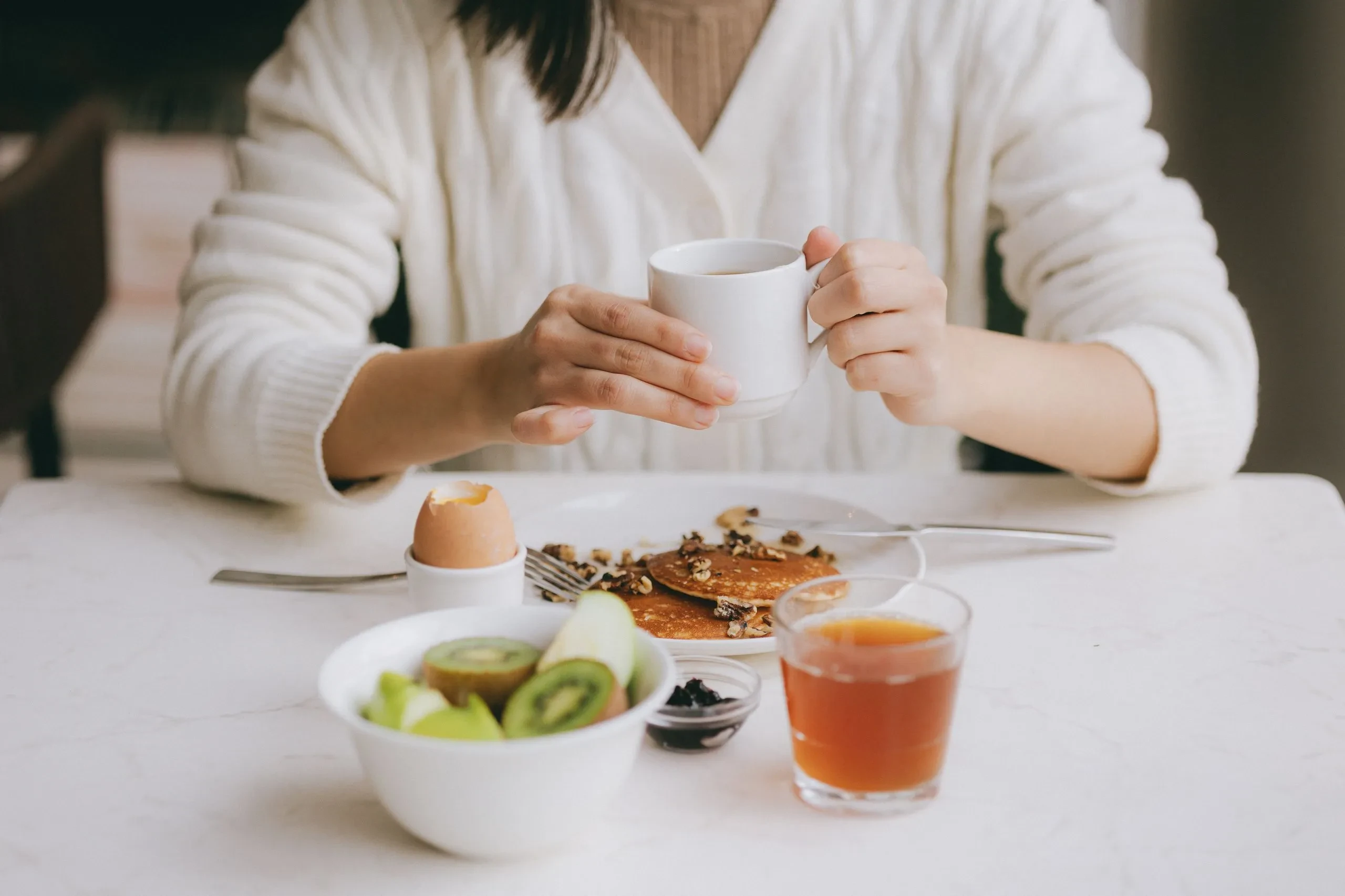 Petit-déjeuner avec pancakes, kiwi, café et jus d'orange.