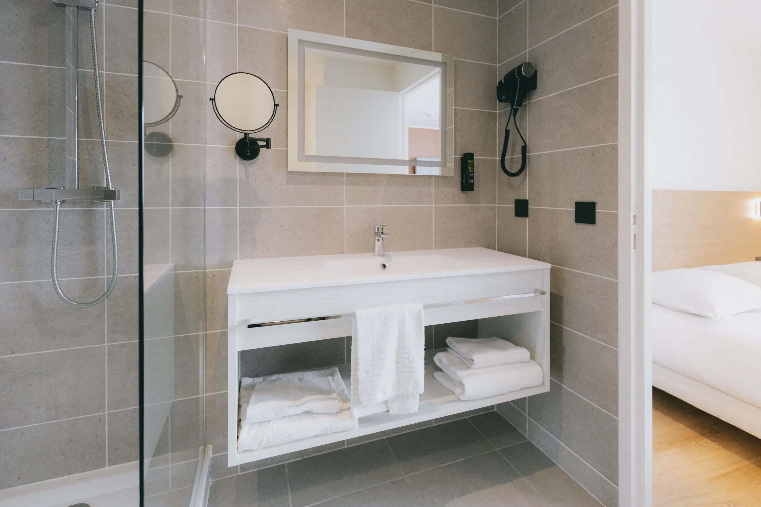 Salle de bain moderne avec douche et lavabo blancs.