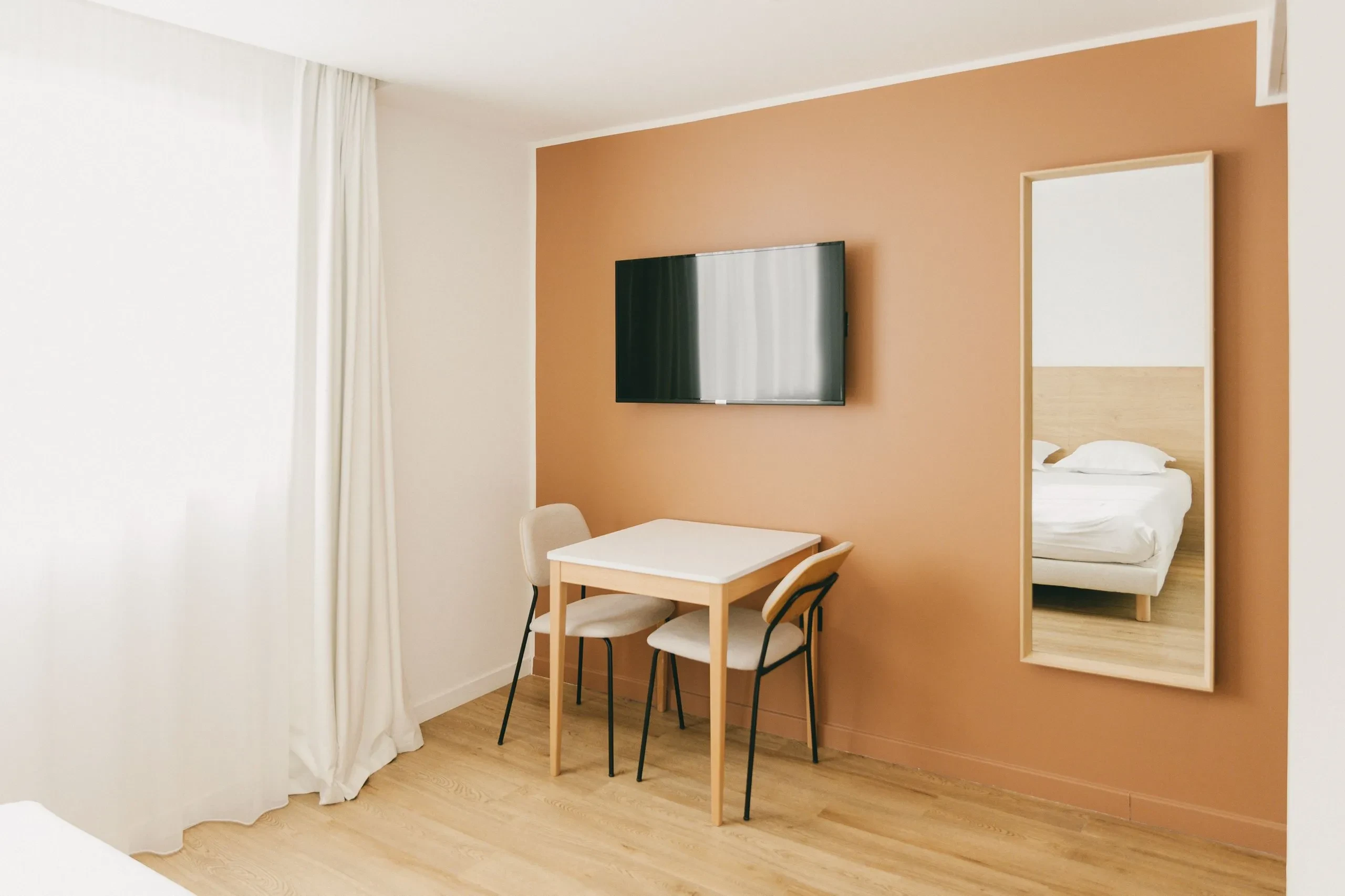 Chambre minimaliste avec table et miroir mural.