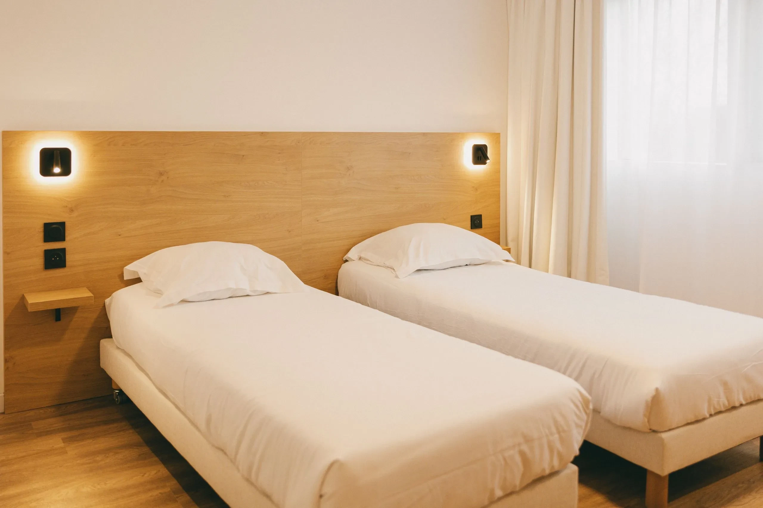 Chambre avec deux lits simples et éclairage moderne.